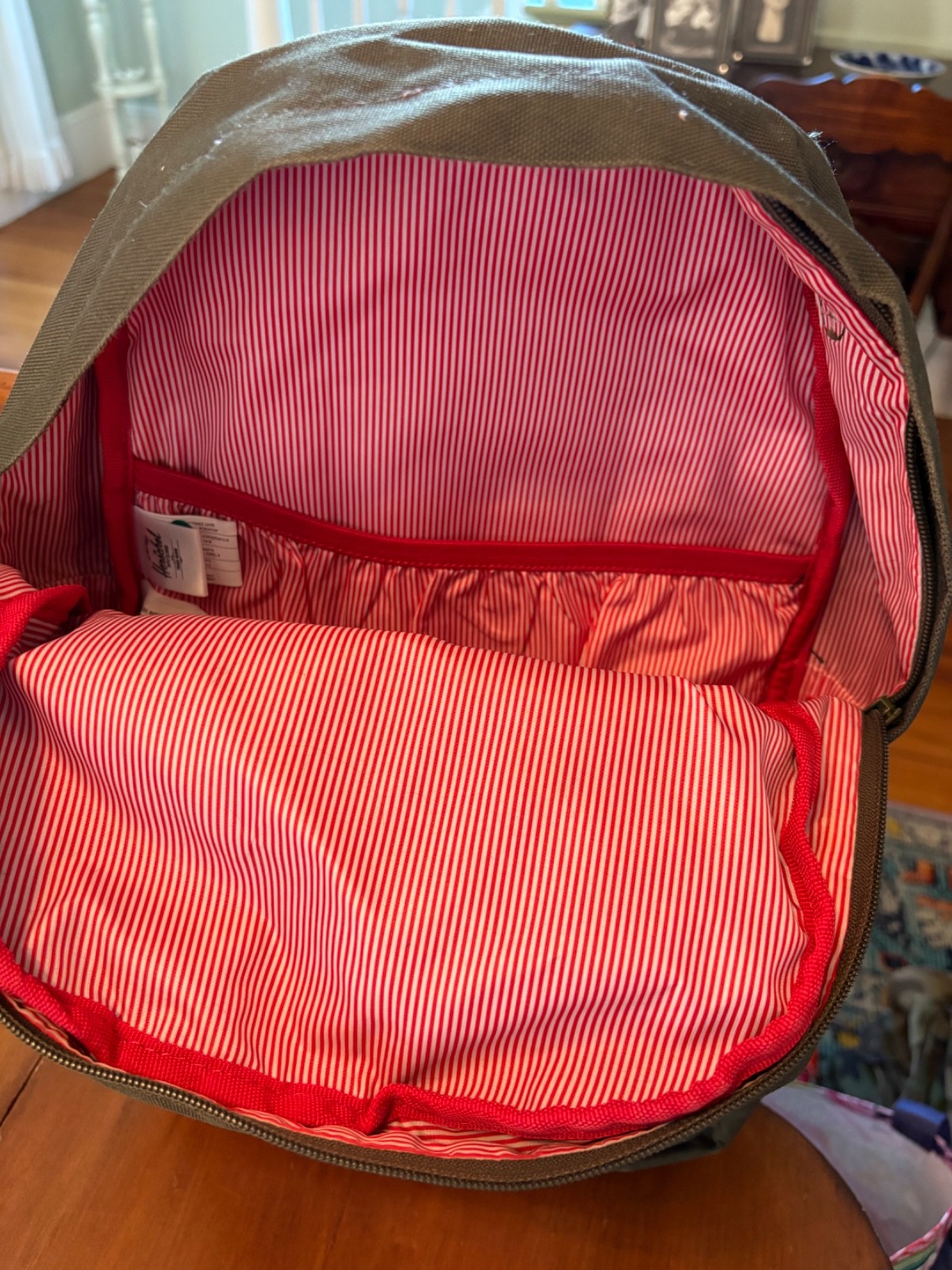 Herschel backpack green and tan with red and white striped interior.