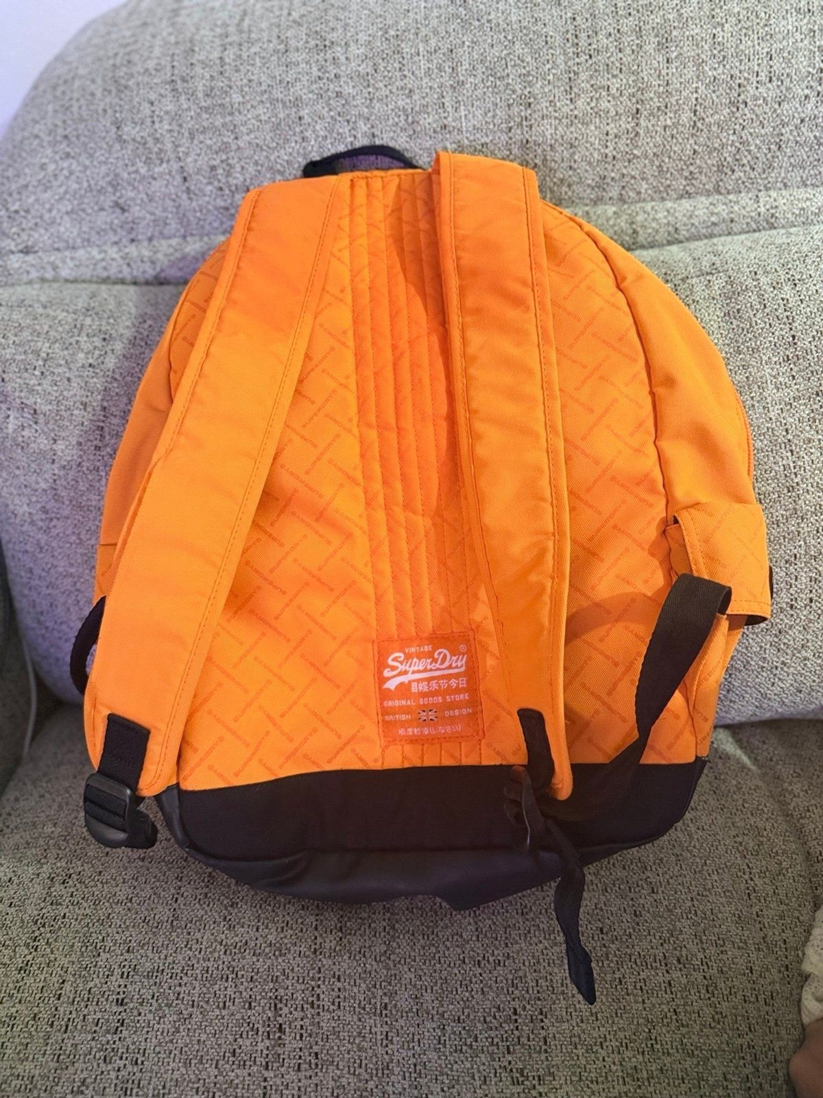 This orange Superdry Men Brand Logo Backpack features a high-build, embossed log